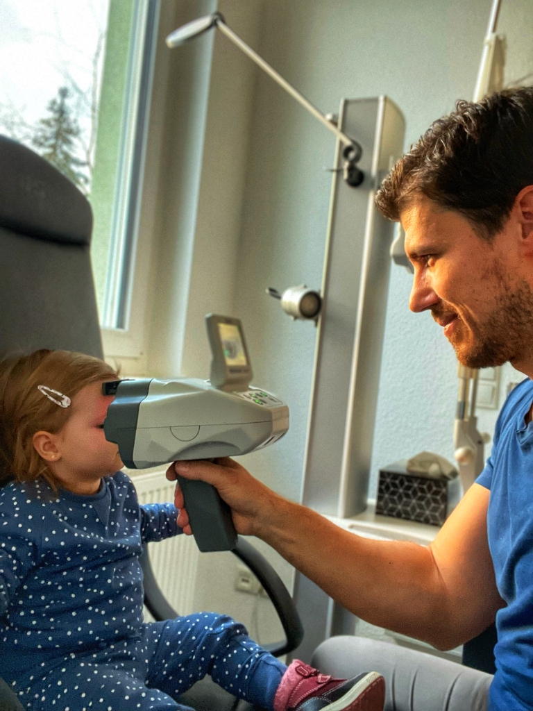 Dr. Ostovic führt eine spielerische Augenuntersuchung bei einem Kleinkind durch